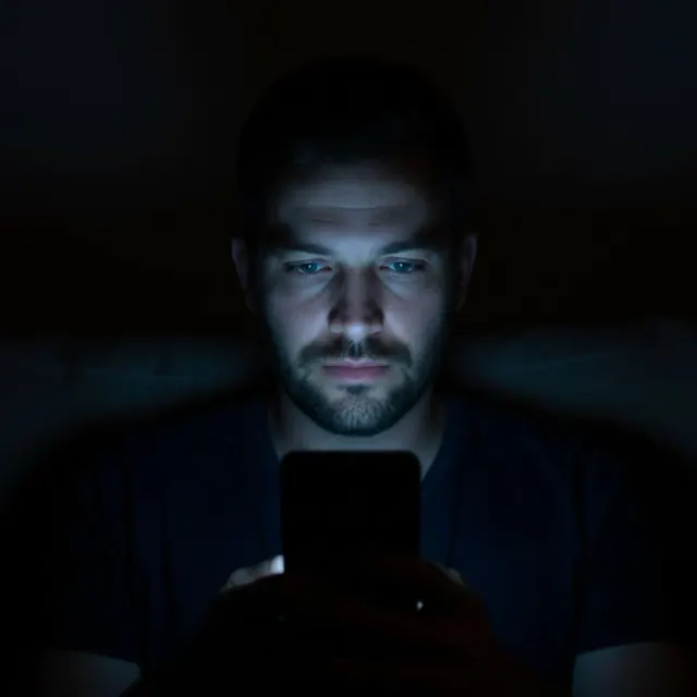 Hombre mirando su teléfono en un ambiente oscuro